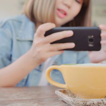 Female blogger photographing green tea cup in cafe with her phone. A young woman taking photo of coffee tea on smartphone, photographing meal with mobile camera.