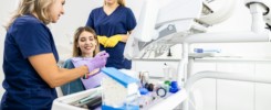 Female dentist with assistant working in dental clinic examining patient teeth.