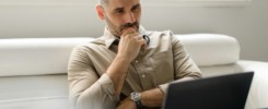 Focused thoughtful businessman using laptop and thinking of project, making decision, looking at