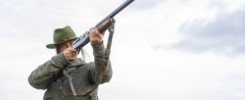 Hunter woman with shotgun hunting in the field.