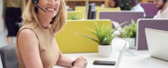 Portrait Of Mature Businesswoman Wearing Phone Headset Talking To Caller In Customer Services Centre