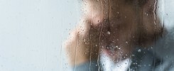 selective focus of crying man behind wet window