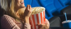 side view of smiling woman in 3d glasses with popcorn watching film alone in cinema