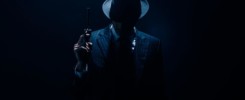 Silhouette of gangster raising gun on dark blue background