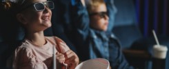 Small children with 3d glasses and popcorn in the cinema, watching film