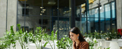 Woman Typing on Laptop Working on Business Plan at Cafe Table in Office Center