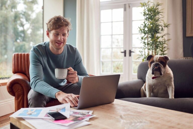 Válassz Vagyon Alap és Portfóliókezelői papírral rendelkező marketingest Man Working From Home In Creative Design Or Marketing Industry Checking Artwork With Pet Bulldog
