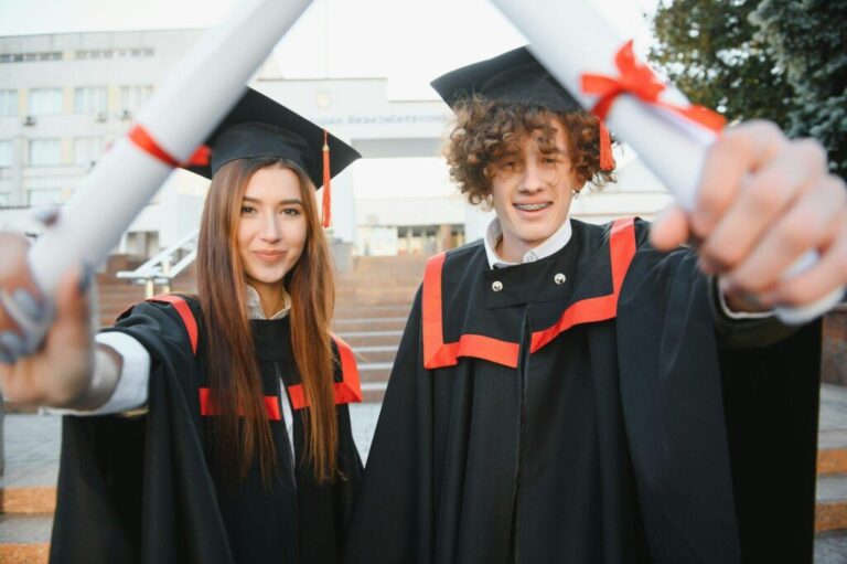 Miért válasszunk Google vizsgákkal rendelkező tanácsadót? Portrait of happy graduates. Two friends in graduation caps and gowns standing outside university