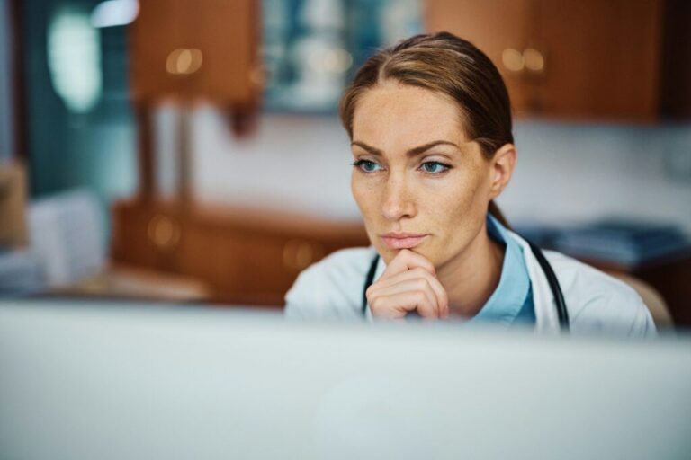 Egészségügyi tudás mint marketingelőny Pensive doctor working on her desktop PC at doctor's office.