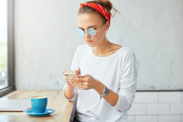 A szövegírás fontossága az online marketingben Attractive female model in stylish shades, recieves feedback on smart phone, bloges sites and posts