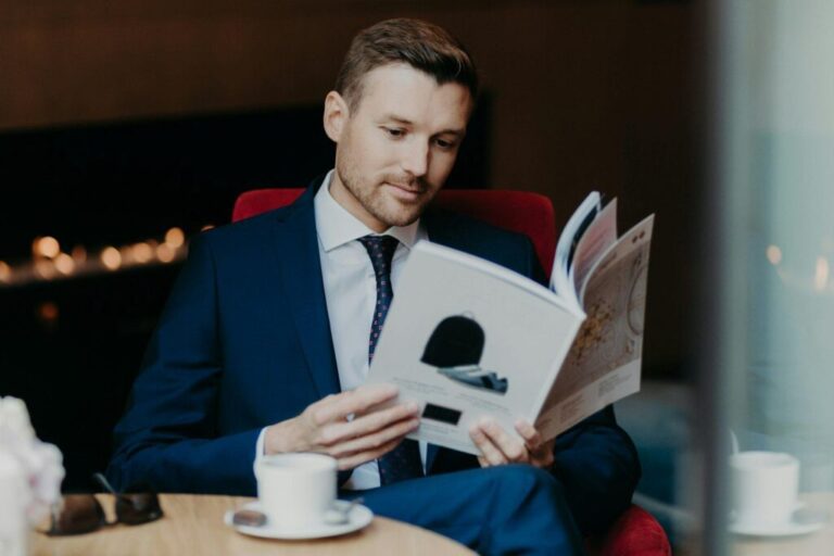 A modern fogyasztói figyelem Concentrated businessman looks attentively in menu while sits in cozy restaurant, drinks coffee