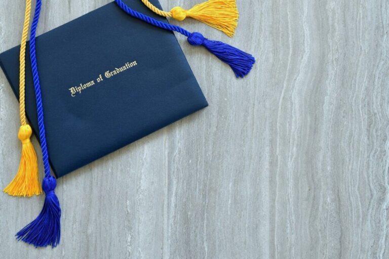 Hogyan lehetek marketinges? Mit tanulok az egyetemen? Flat lay of a Diploma of Graduation with honor cords on a simple wooden background.