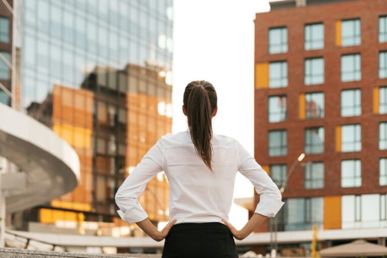 A marketing tanácsadó szerepe vállalkozásoknál Rear view of businesswoman looking business buildings