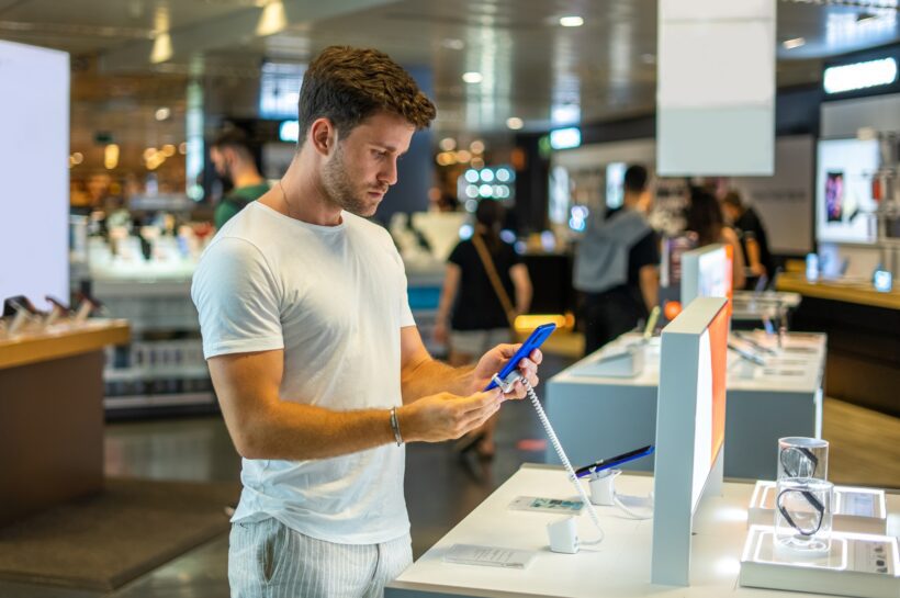 Buyer with smartphone in electronics shop