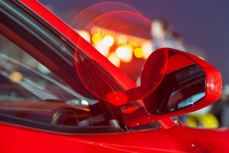 Mit tanulhatunk a Ferrari marketingeseitől? Luxury red car, closeup details with city lights behind it. Bokeh.