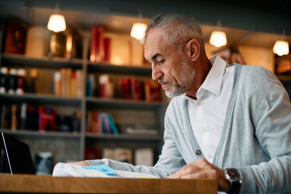 Mature student learning from book in a library.