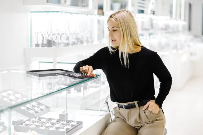 Saleswoman calculating price using calculator in jewelry shop