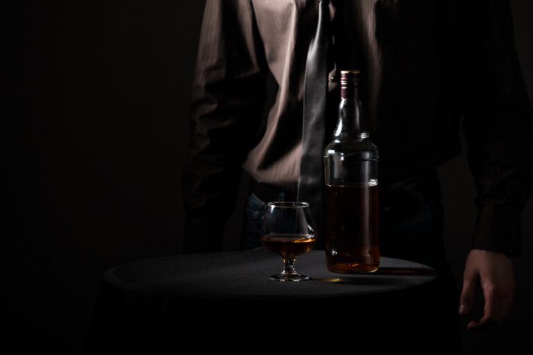 A munkahelyi alkoholizmus rejtett okai Bottle with an alcoholic drink and a glass