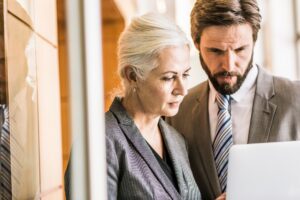 Businesspeople wearing suits looking at laptop