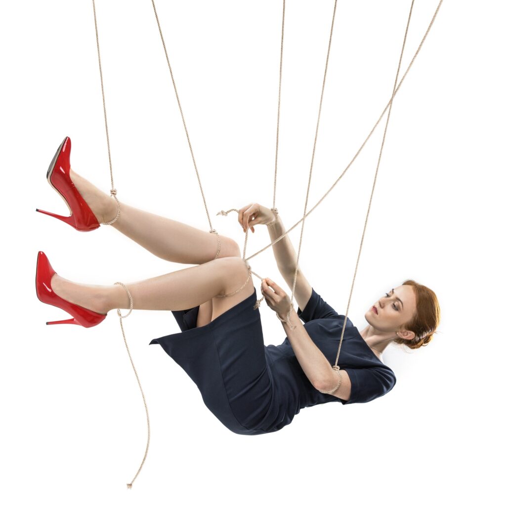 businesswoman trying to break free while hanging on manipulating ropes isolated on white