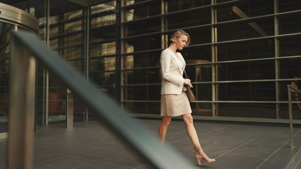 Businesswoman with blond hair wearing beige suit leaving business center