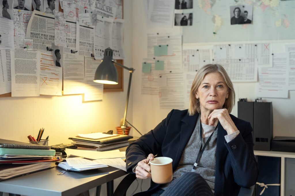 Contemporary agent of FBI in formalwear sitting in armchair by desk