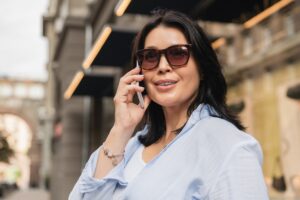 Middle-aged mature caucasian woman in sunglasses talking on smart phone with boss