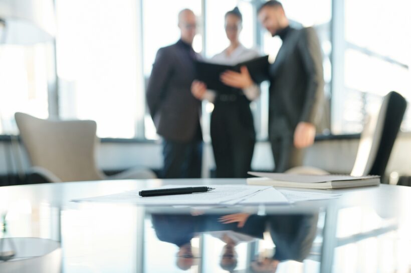 Pen on papers and notebook with business partners having negotiation