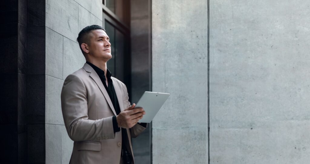 Portrait of a Young Striving CEO or Leader Working on Tablet. Businessman Standing at the City