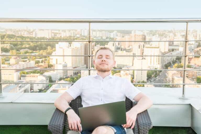 Kinek a feladata a munkahelyi jóllét fokozása? Satisfied and relaxed man with the laptop after well work done on an open terrace