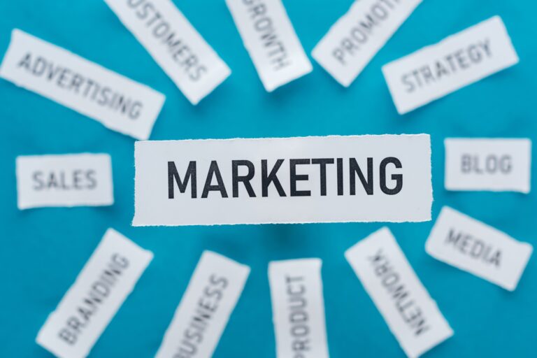 Online marketing kezdőknek selective focus of word marketing and components related to marketing on pieces of paper on blue