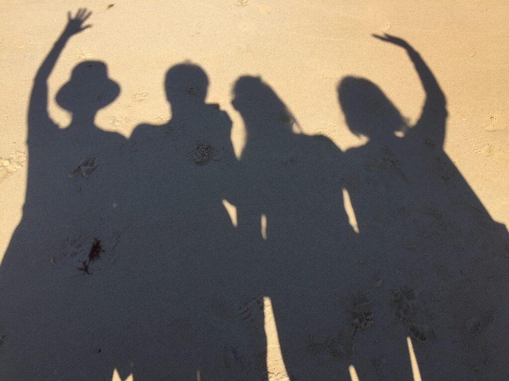 Shadows of four friends on sand