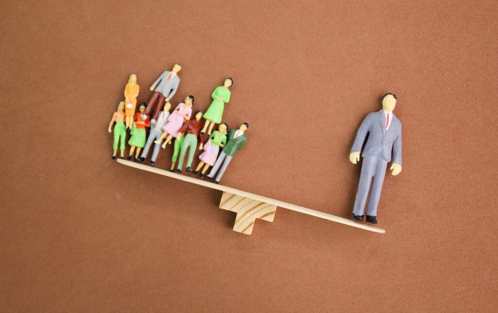 the balance of miniature people workers and leaders. the leader is heavier.