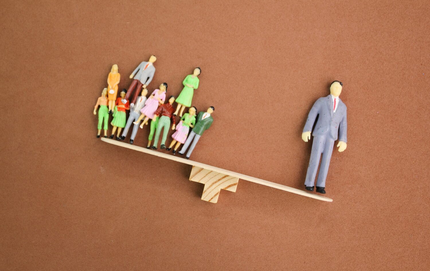the balance of miniature people workers and leaders. the leader is heavier.