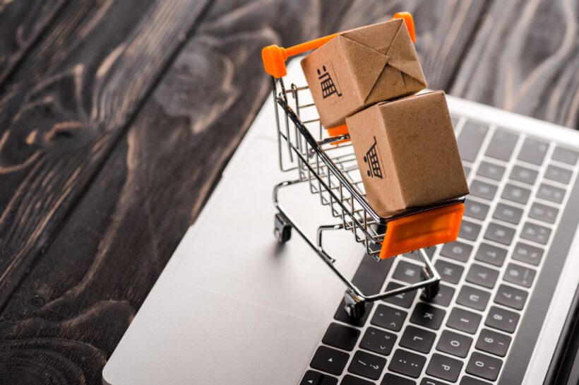 toy boxes in small shopping cart on laptop, e-commerce concept