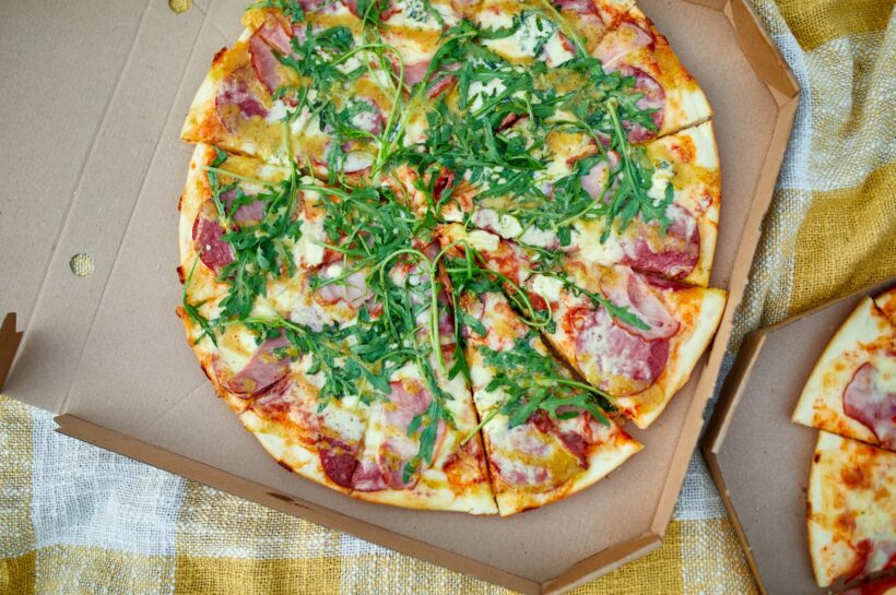 Two pizzas in the food carton on the grass, picnic concept, top view, copy space