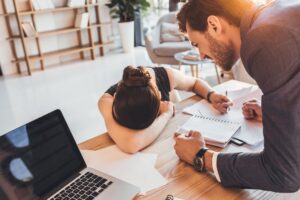 Young secretery crying on desk while her furious boss screaming at her