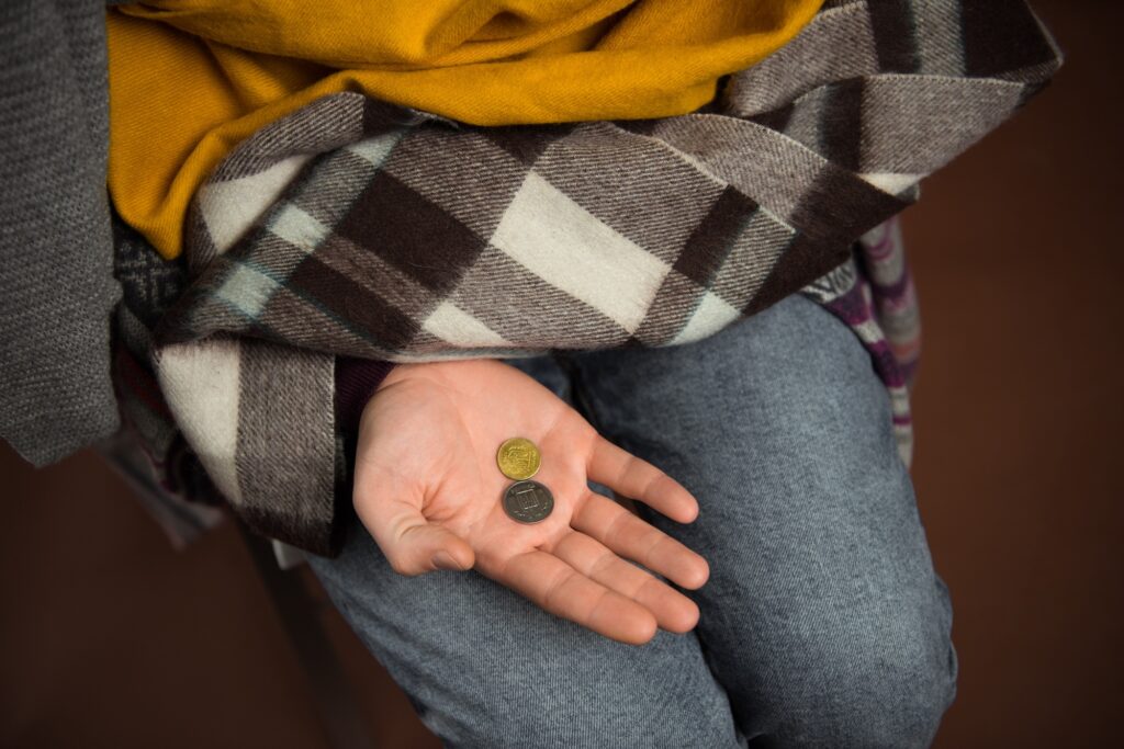 Cropped image of poor man holding coins on hand isolated on brown