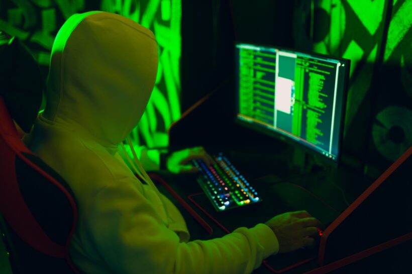 Google Ads fiókok feltörése: módszerek és védekezés Hacker in hoodie working hacks code site on personal computer with green light