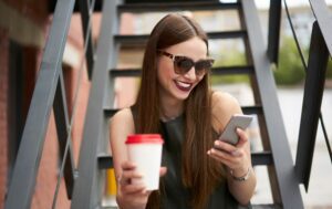 Happy Caucasian tourist with coffee to go reading funny publication in networks