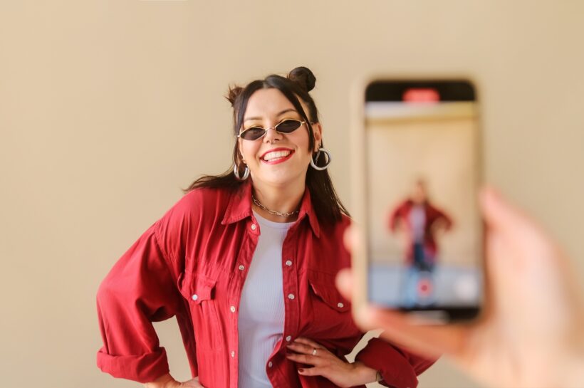 Stylish trendy woman recording dance video for social media account on phone.