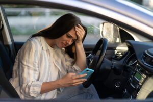 Unhappy girl cry reading sms message in smartphone driving car. Upset female break up with boyfriend