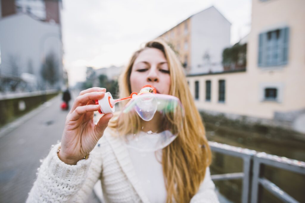 Young woman palying bubble soap outdoor