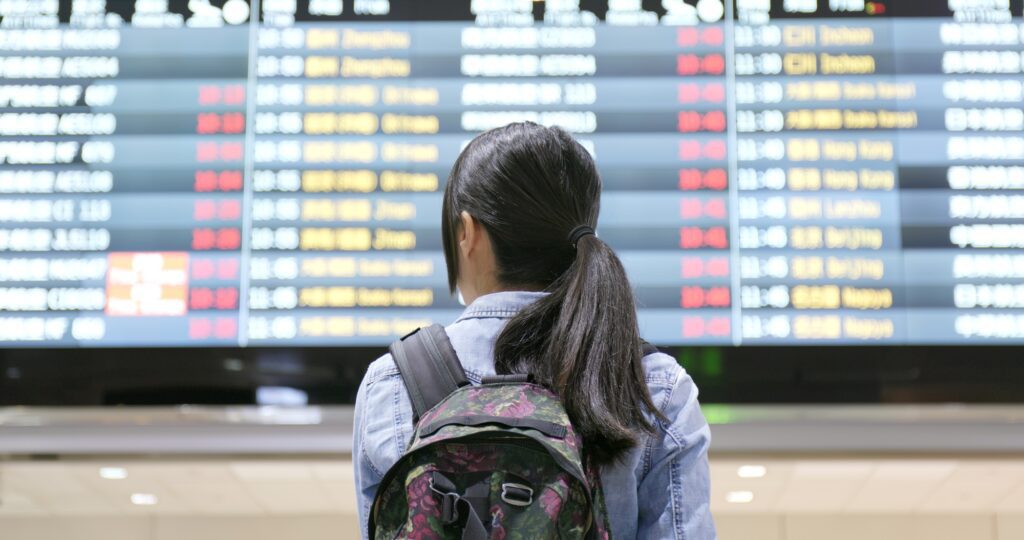 Young woman traveler looking for the flight number number at airport