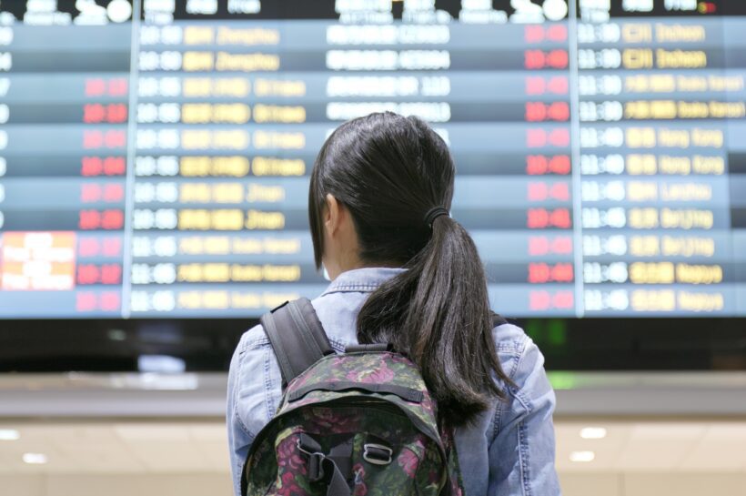 Young woman traveler looking for the flight number number at airport