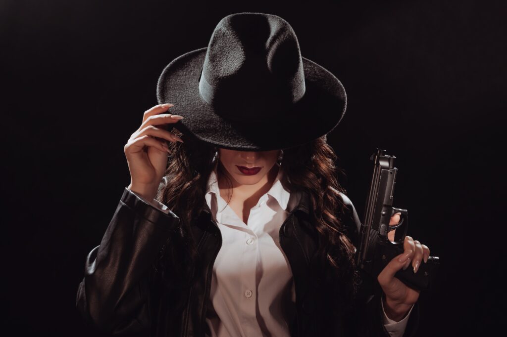 Silhouette of a female detective in a coat and hat with a gun in her hands.